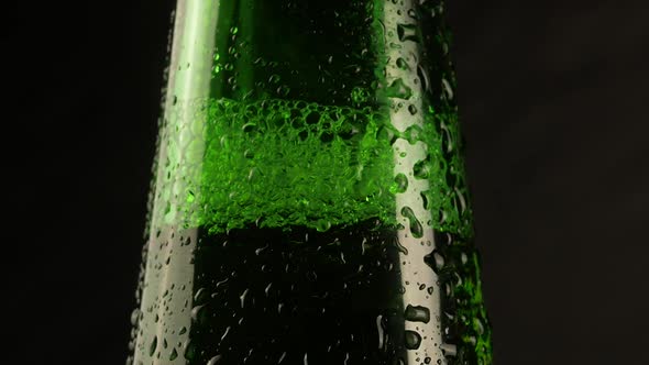 Drop of condensation drips on beer bottle glass. Water drops falling down