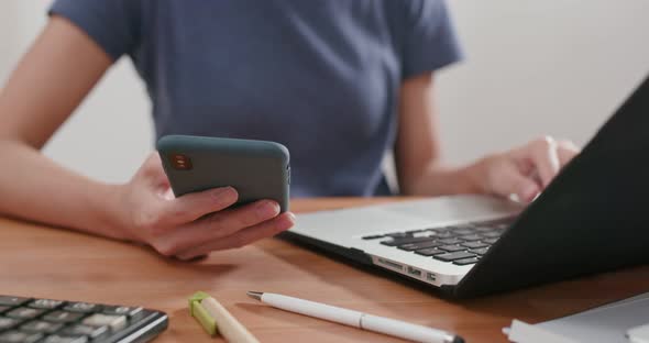 Woman work on computer and use of cellphone at home alt