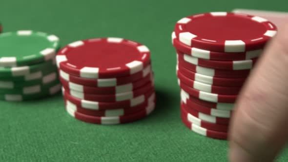 A Closeup Poker Shot of Color Chips Man's Hand Doing a Bet Red Chips Sliding Toward Camera