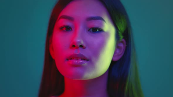 Studio Portrait of Young Millennial Korean Lady Turning to Camera and Smiling Posing in Bright Neon alt