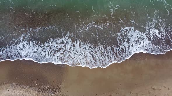 Beautiful aerial view of the drone, the ocean washes the golden shore with these waves.