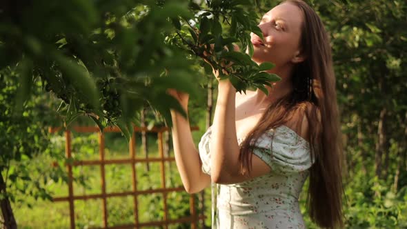 Woman Touching Tree Branches in Garden