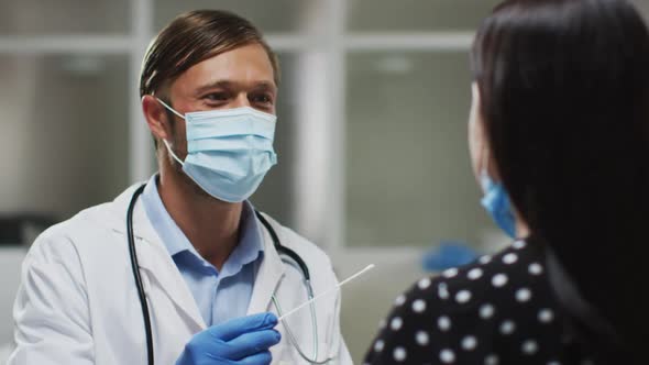Caucasian male doctor wearing face mask and gloves taking swab test from patient alt