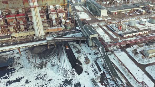 Yellow excavator smoothes black ash from coal under the bridge in the territory alt