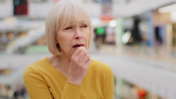 Mature Caucasian Unwell Woman Standing Indoors Coughing Covers Mouth with Hands Elderly Unhealthy alt