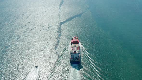 A Cargo Ship Transports Containers Towards Open Ocean Waters alt