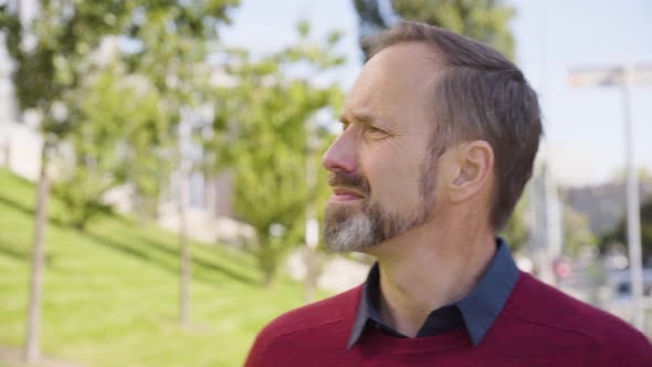 A Middleaged Handsome Caucasian Man Looks Around in a Street in an Urban Area  Closeup alt