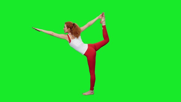 Young Slim Woman Standing On One Leg While Practicing Yoga on Green Screen 
