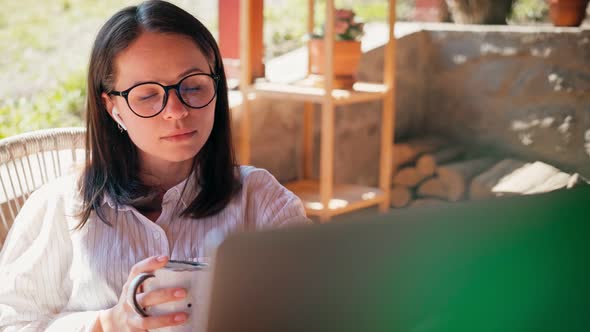 A Young Woman Freelancer Working on Her Laptop While Sitting on the Terrace alt