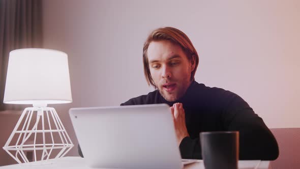 Young Caucasian Teacher Working on Laptop with Cup of Coffee Nearby alt