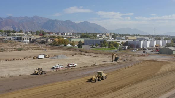 Aerial shot of a road grader and Bulldozer roller compacting and leveling dirt at a construction sit alt