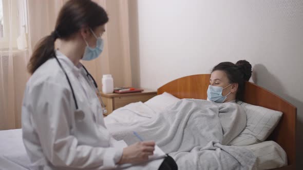Side View Young Ill Woman Lying in Bed Answering Questions of Blurred Professional Doctor in alt