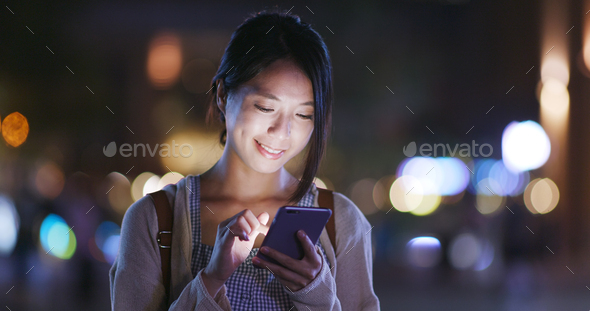 Woman use of smartphone in the city at night