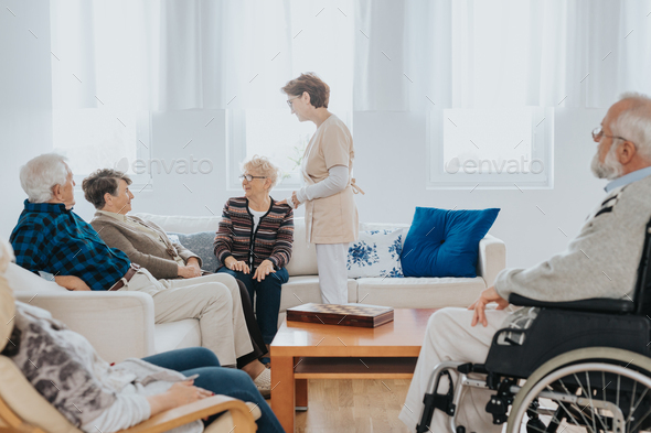 Head nurse is talking to new patients sitting on the sofa in a retirement home