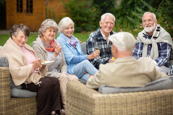 Group of senior friends sitting together in the garden during spring party Stock Photo by bialasiewicz