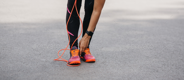 Cardio training and athletics. African american woman with fitness tracker straightens sneakers