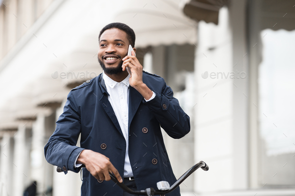 Handsome business man talking on phone holding bike