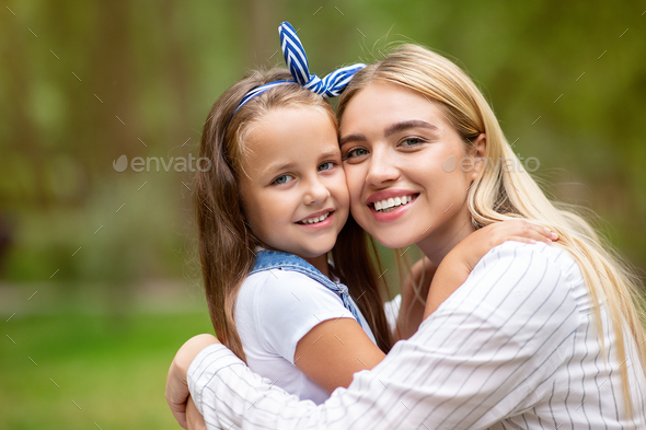 Happy Mom And Daughter Embracing Smiling To Camera In Park