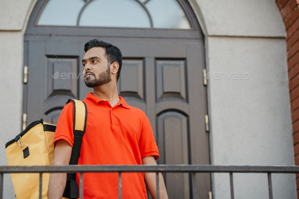 City delivery service and search customer address. Attractive man with yellow backpack, near front - Stock Photo - Images