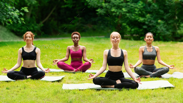 Outdoor yoga class. Group of diverse girls doing breathing exercises or meditation in nature