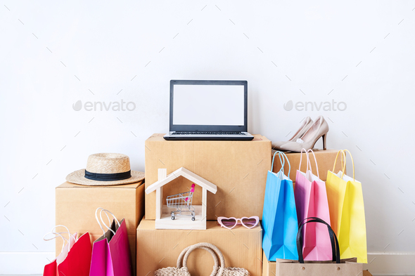 Colorful shopping bag with stack of cardboard boxes and fashion items at home