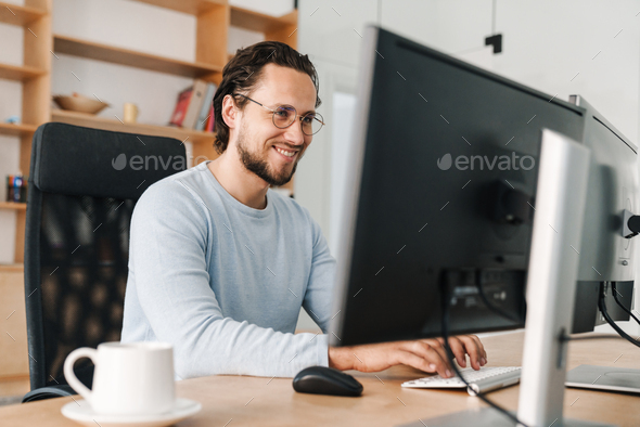 Image of smiling unshaven programmer man working with computer