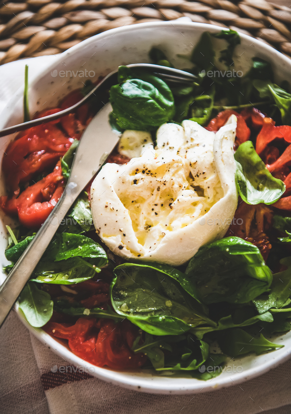 Italian salad with Buratta cheese in white bowl, close-up - Stock Photo - Images