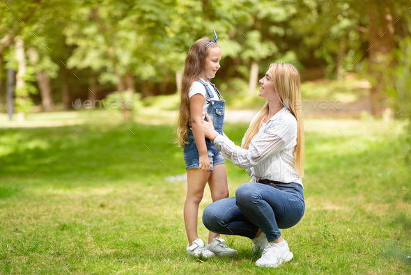 Happy Mother And Little Daughter Talking Walking In Park Outdoors