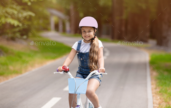 Carefree Kid Girl Riding Bicycle Outside, Wearing Protective Helmet