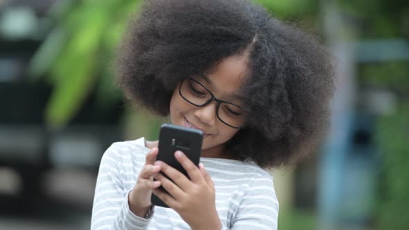 Young Cute African Girl with Afro Hair Using Phone in the Streets Outdoors alt