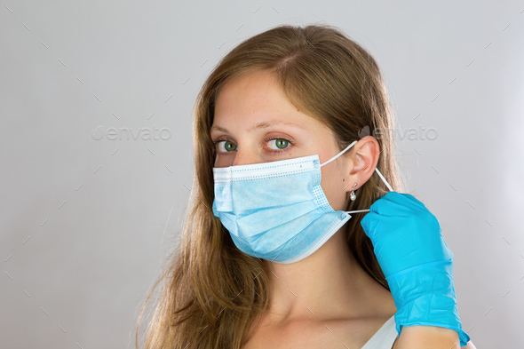 Young blonde woman putting on face mask in studio