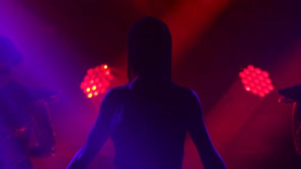 Silhouette of Dancing Joan of Arc on Stage in a Dark Studio with Smoke and Neon Lighting. A Bright alt