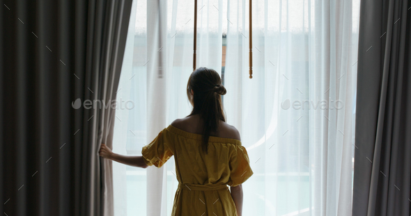Woman open the curtain at morning
