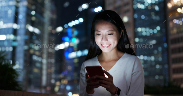 Woman work on smart phone in city over business tower background