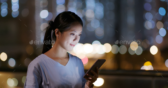 Woman look at the smart phone in city at night