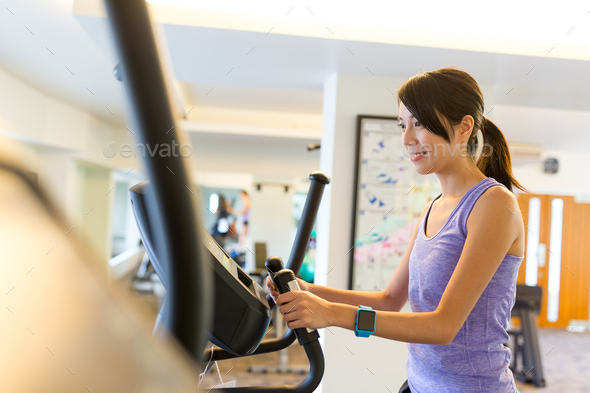 Woman training on Elliptical machine in gym