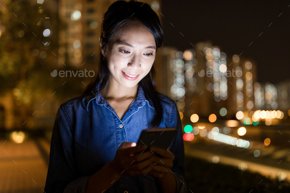 Woman using mobile phone in city at night
