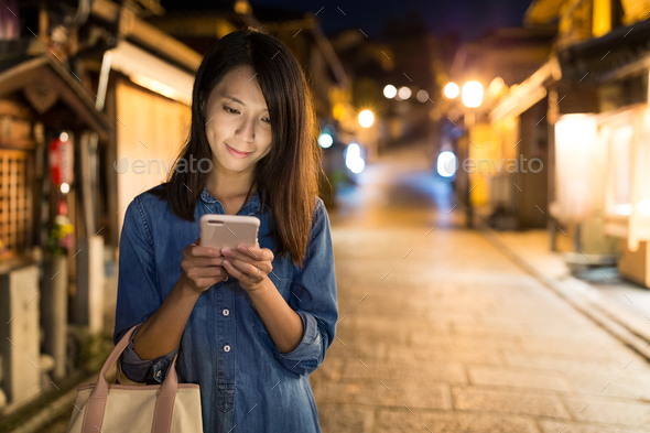 Woman using mobile phone in Kyoto city at night