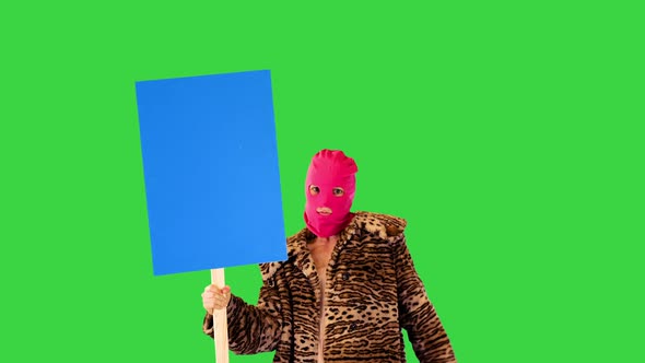 Girl in Pink Balaclava Dances Slightly Holding a Banner and Pointing at It on a Green Screen Chroma