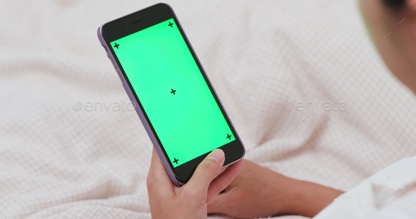 Woman use of smart phone with chroma key on bed
