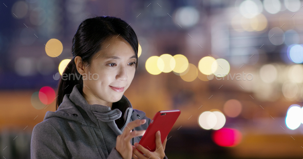 Woman use of cellphone in the street at night