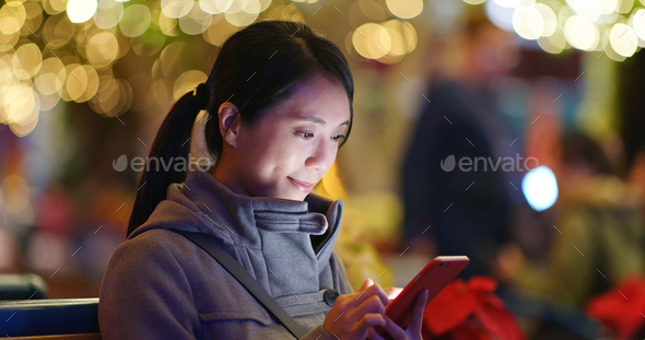 Woman use of mobile phone over golden light blur background