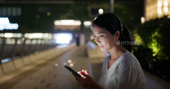 Woman uses mobile phone in Hong Kong at night