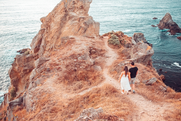 Couple walking on a cliff near the ocean