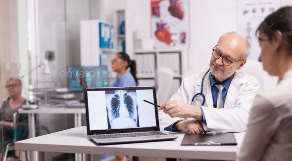 Senior doctor pointing at lungs x-ray - Stock Photo - Images