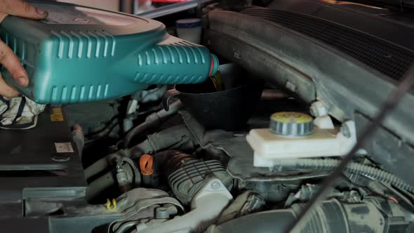 Close Up Futage of Pours Oil Into the Engine in Maintenance Car Garage alt