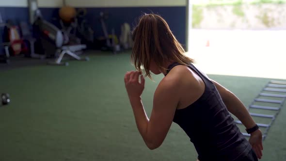 Female athlete performing ladder sprints alone in a gym alt