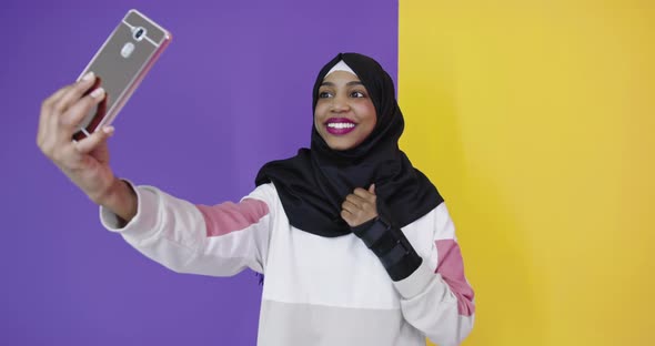 Portrait of Smiling African Black Muslim Girl Posing at Color Studio Background Taking Selfie Photo alt
