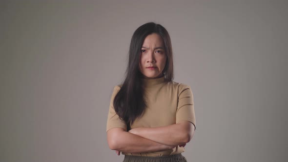 Asian woman angry showing arms crossed standing isolated on background.