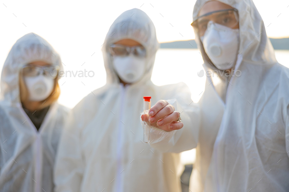 Group of researchers holding water sample at beach - Stock Photo - Images